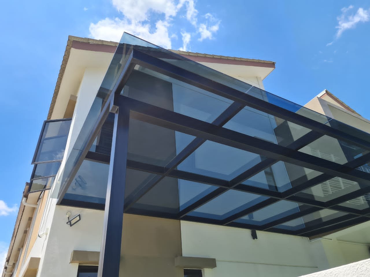 Laminated tempered glass roof awning over a residential balcony
